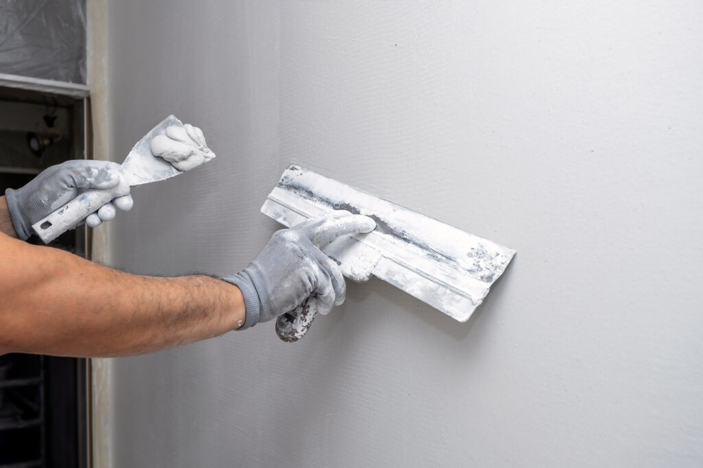 Stukadoor werkt een muur glad met een plamuurmes